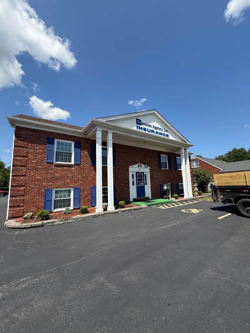 A brick office building with tidy foundation plantings and a clean parking lot, with a work trailer parked at the side