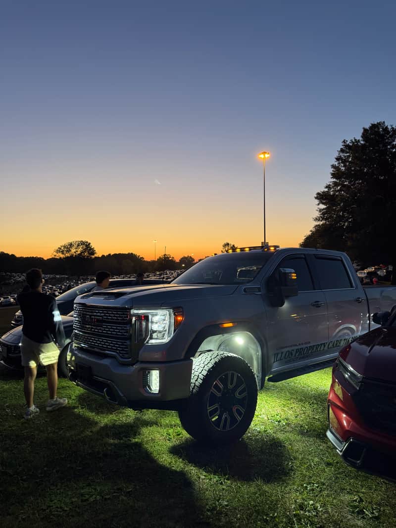 A crew pickup truck parked at dusk with the sun setting behind the tree line